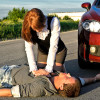 a lady performing cpr near a car on a young man outside