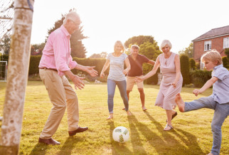 a family of varying generations playing football with a house in the background