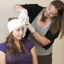 First Aid Bandage Practice a woman practicing putting a bandage on a persons head