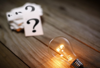 A stack of question mark cards next to a glowing light bulb