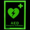 aed location sign showing a green glowing heart with a lightning bolt and text on a dark background