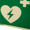 A close up image of a panoramic aed wall sign with a heart logo with a lightening bolt through it with a first aid cross