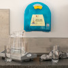 LifeVac wall mounted kit in a blue case fixed to a kitchen wall above a tray with a jug and glasses of water