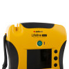 A close-up of the green power button on a yellow defibrillator