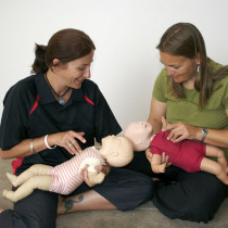 Paediatric First Aid Training a couple of woman practicing paediatric cpr on baby annes