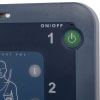 A close-up of the green power button on a blue defibrillator