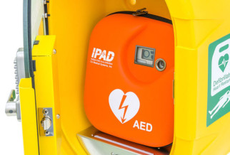 an orange defibrillator in a yellow cabinet
