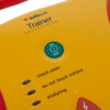 a close view of the green power button on the trainer unit with leds and text stating check pads, do not touch patient and analyzing