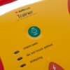 Closeup of the button and labelled instructions on the defibtech lifeline aed trainer unit in yellow and red