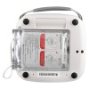 Back view of an AED training unit showing a transparent compartment containing sealed training pads with printed diagrams and multilingual instructions