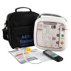 Complete AED training kit laid out, including the AED Trainer device, black carrying case, remote control, electrode pads, and instruction materials