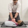 Man performing compressions on laerdal little anne qcpr dark training manikin lying on floor