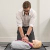 Person performing compressions on laerdal little anne qcpr light training manikin lying on the floor