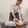 Person demonstrating the laerdal little anne qcpr light training manikin lying on a mat during training session