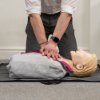 Person practising chest compressions on a laerdal little anne qcpr light training manikin on the floor
