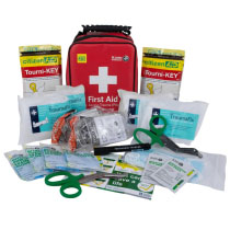 Stjpact2 Tourni Key Kit Contents a red plastic carry case with a black handle with a white cross and the words first aid. In front is the contents of the trauma kit including blue gloves, tourni-keys, clothing shears and bandages