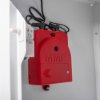 Closeup of the red alarm unit inside a zoll aed plus wall mount cabinet showing its details and wiring