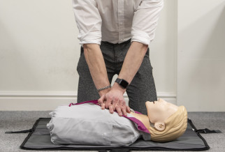 A young man performing CPR on a training Manaquin